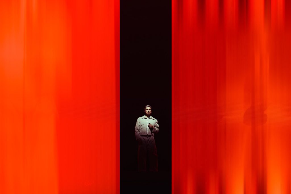 Orelsan on stage against a red backdrop during his concert at ING Arena